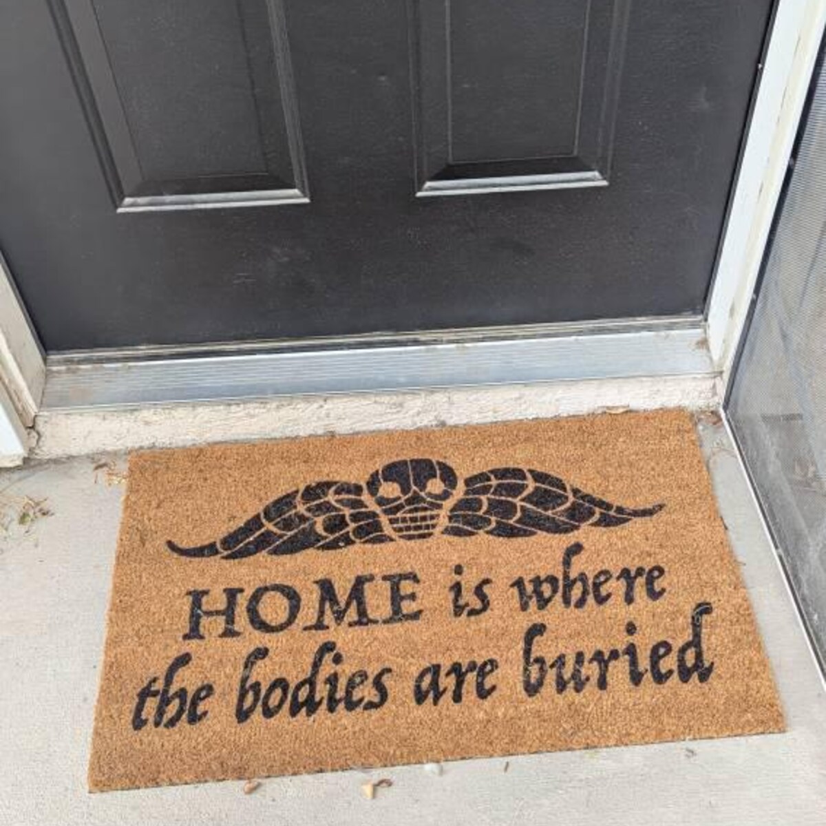A funny horror-themed Halloween doormat on a real porch