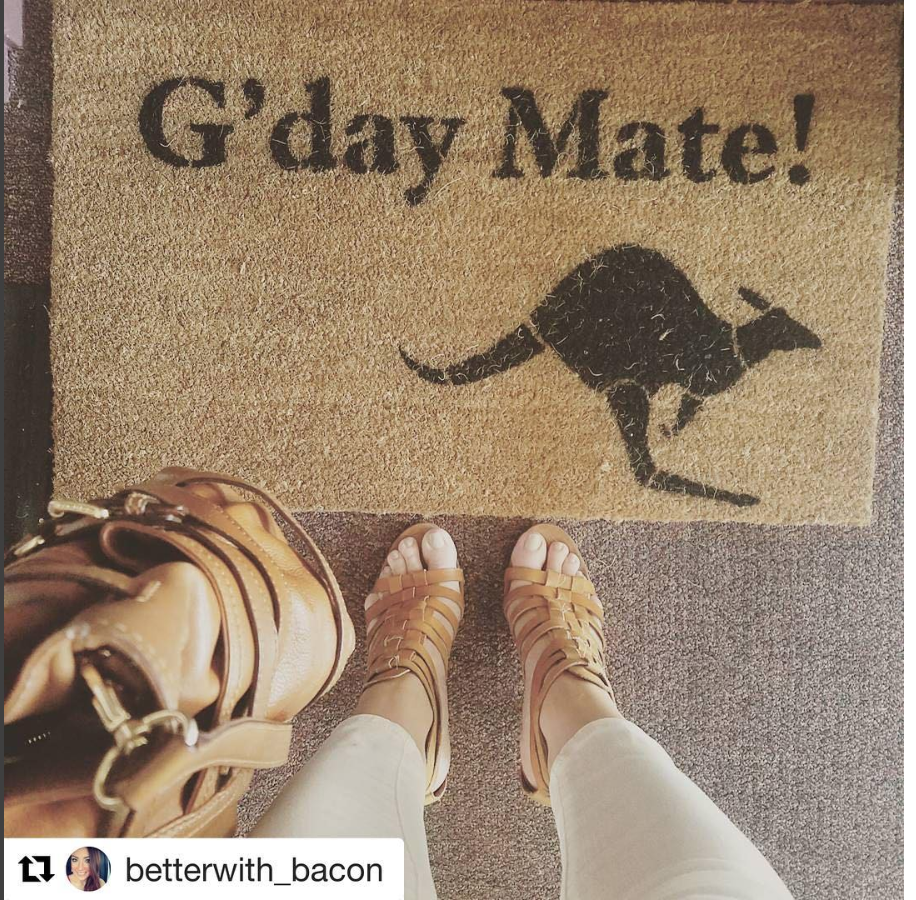 A funny doormat "G'day mate!" marking a college dorm room door in an identical hallway.