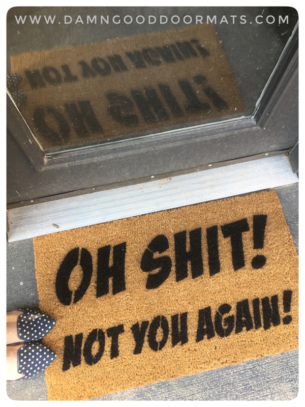A sarcastic funny doormat at a doorway surrounded by guests' shoes.