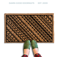 A pair of feet wearing green shoes stands on a subtle patterned FDT Fuck Donald Trump doormat