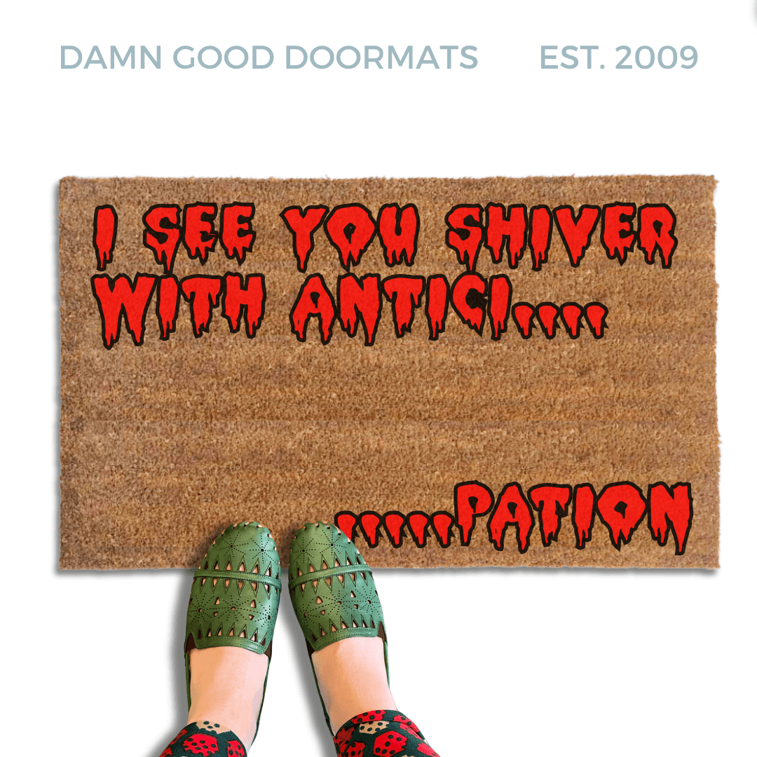 Rocky Horror Movie Quote "I see you shiver with anticipation" doormat written in red bloody letters. A person in green shoes stands on the mat