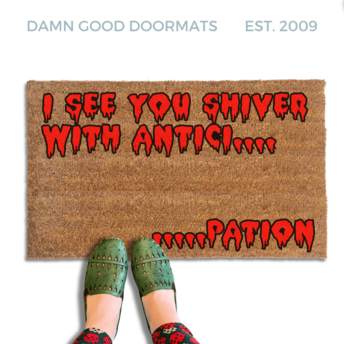 Rocky Horror Movie Quote "I see you shiver with anticipation" doormat written in red bloody letters. A person in green shoes stands on the mat